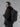 Man wearing a black backpack against a gray background