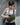 Woman wearing a green sling bag against a gray wall