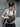 Woman wearing a green sling bag against a gray wall