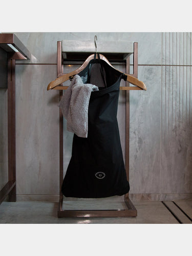travel laundry bag on wooden hangers against a tiled wall.