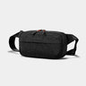 Black sling cross-body bag on a light gray background