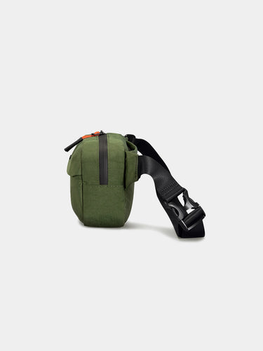 Green waist bag with a black strap on a light gray background