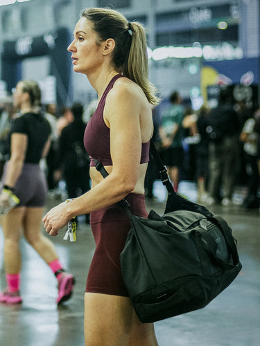 Woman carrying the Flex Convertible Duffel 27L in black at a gym event