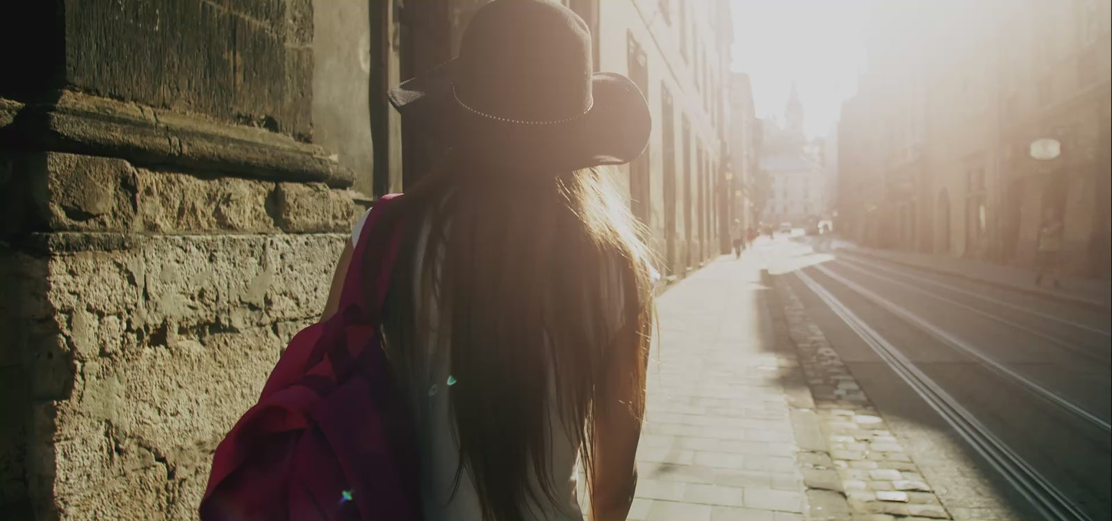 person with backpack in sunlit street